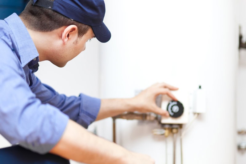 Help! I Have No Hot Water. Photo of a technician adjusting a dial on a water water.
